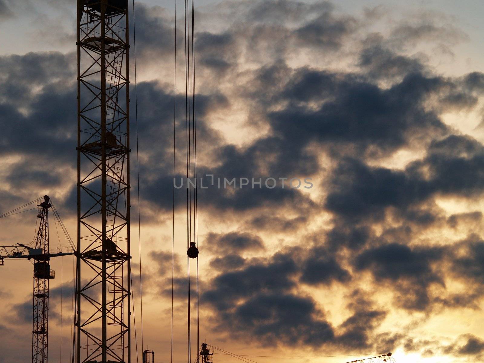 Elevating cranes and sky. Sunset after rain.     