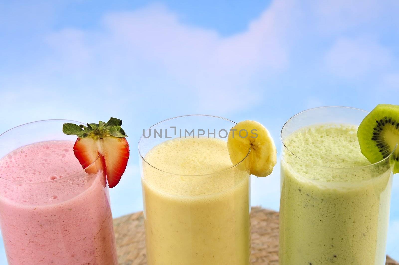 Assorted fruit and berry smoothies on blue sky background