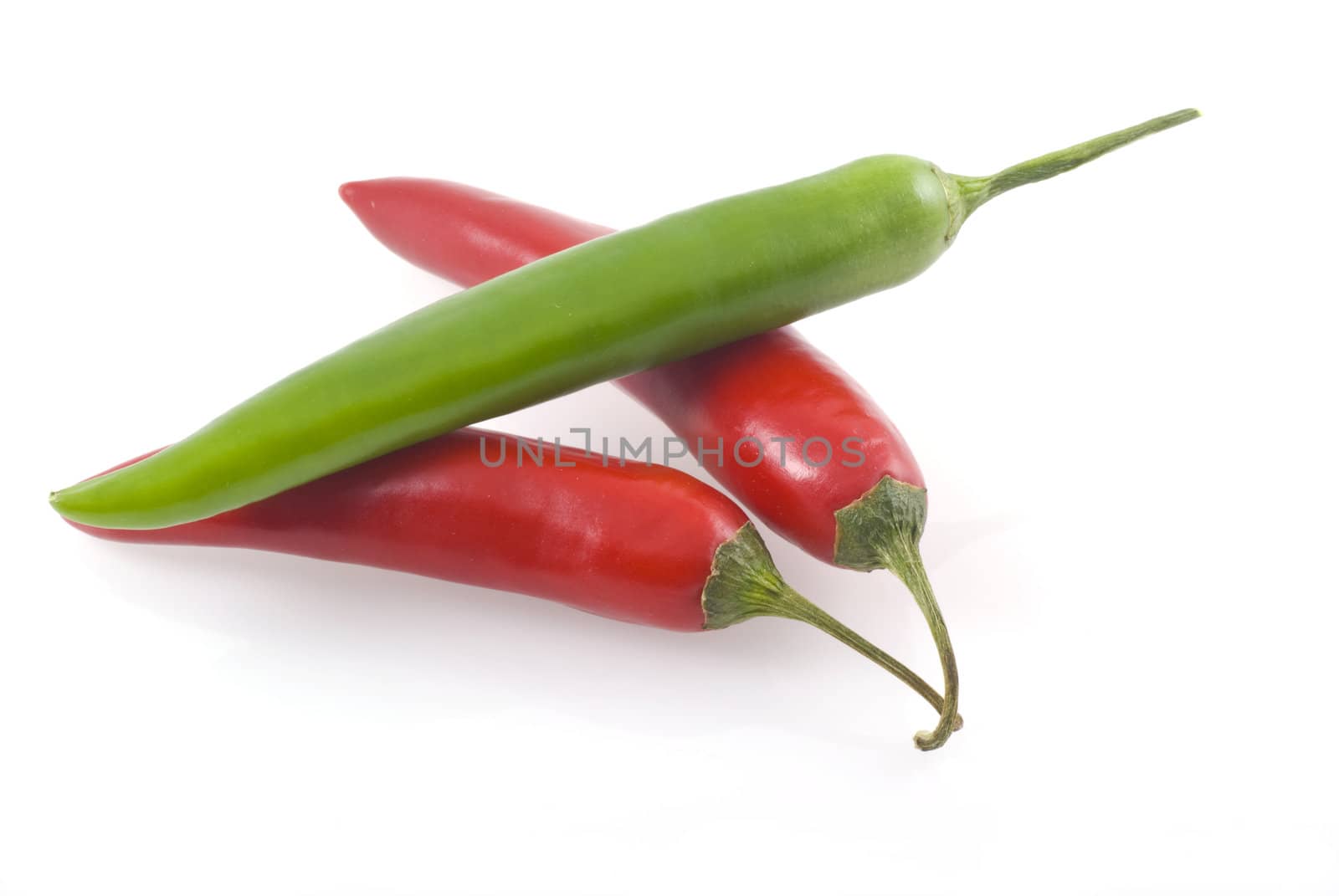 Two red and one green chili pepper isolated on a white background.