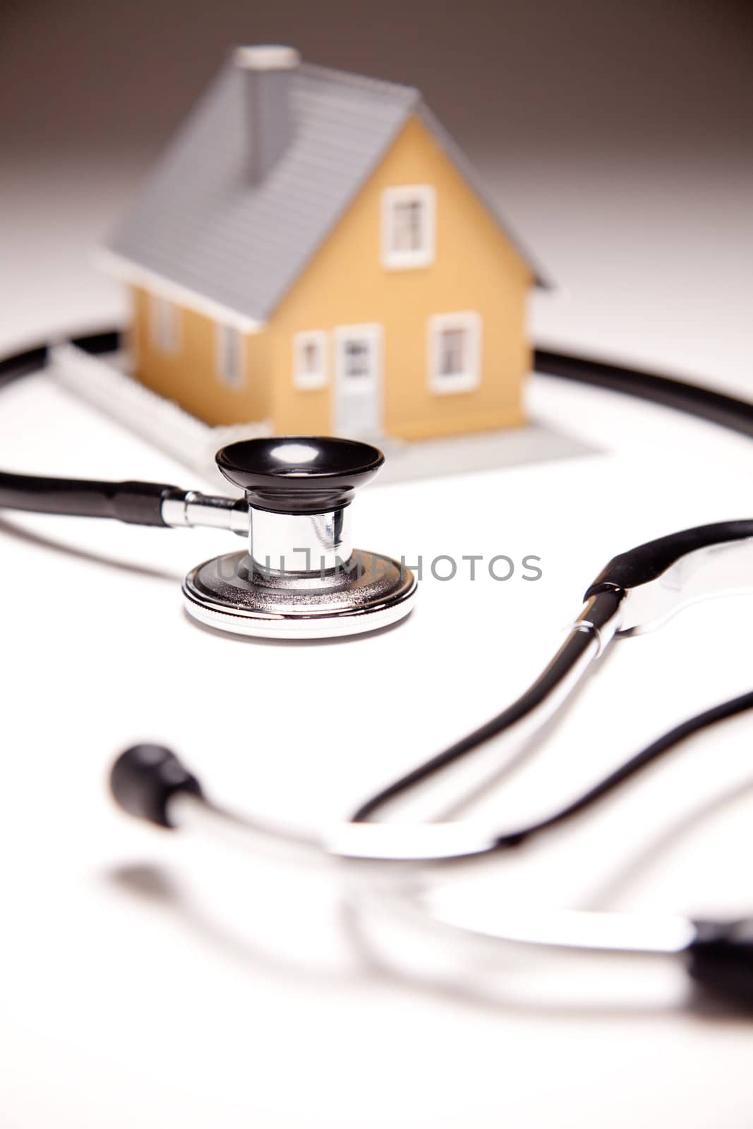 Stethoscope and Model House on Gradated Background with Selective Focus.