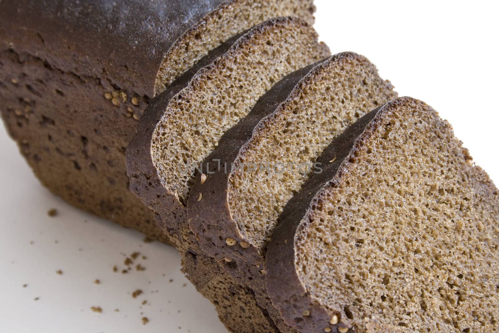 Loaf and slices of black bread with carum isolated on white background