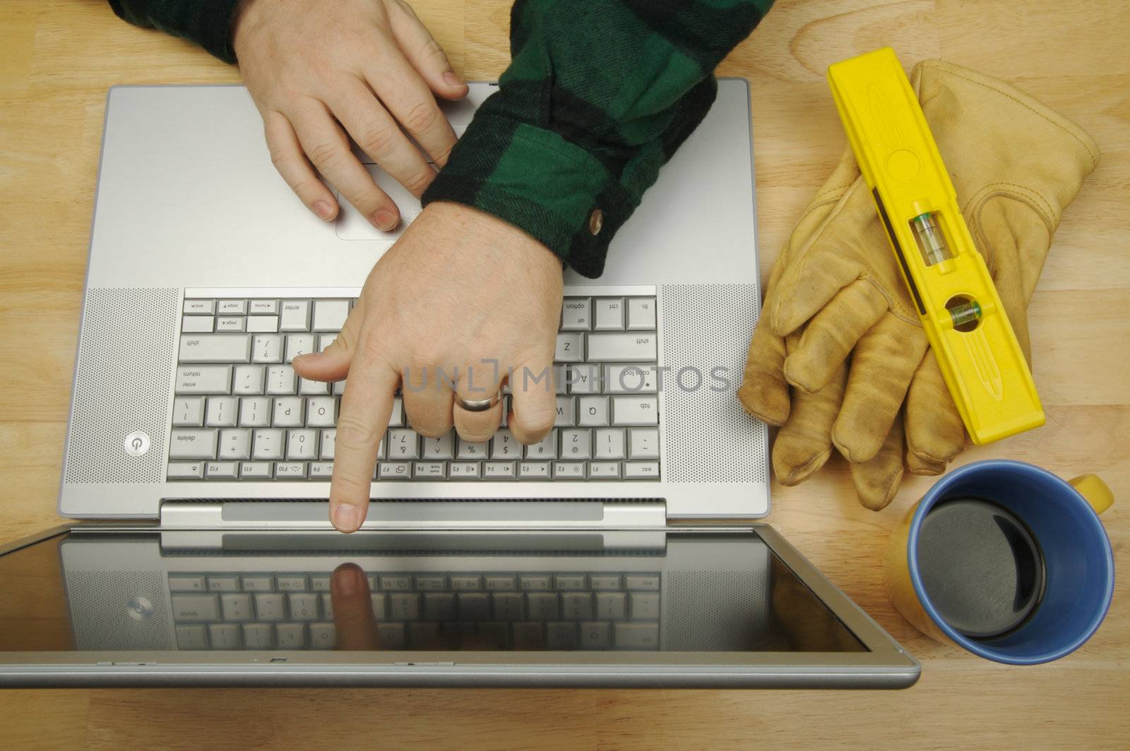 Contractor Points & Reviews Project on Laptop with level, gloves and coffee to his side. Great image for online information regarding home improvement, additions, remodeling or construction.