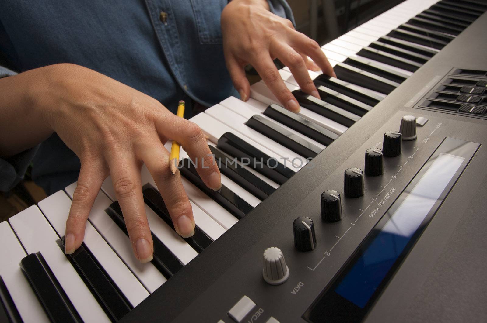 Woman's Fingers with Pencil on Digital Piano Keys