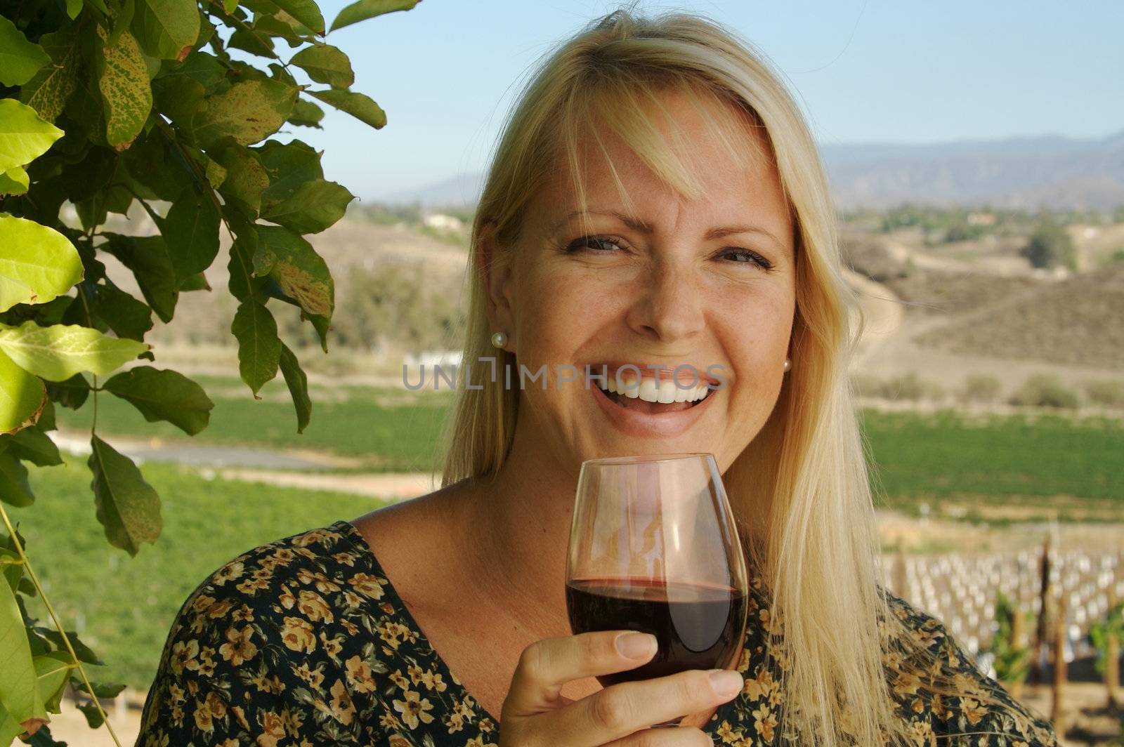 Attractive Woman Sips Wine at a Winery in the country.