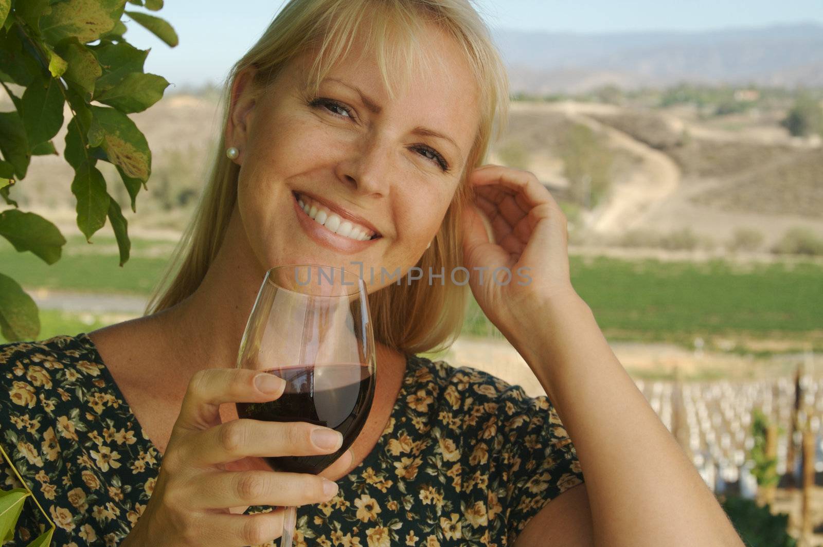 Attractive Woman Sips Wine at a Winery in the country.