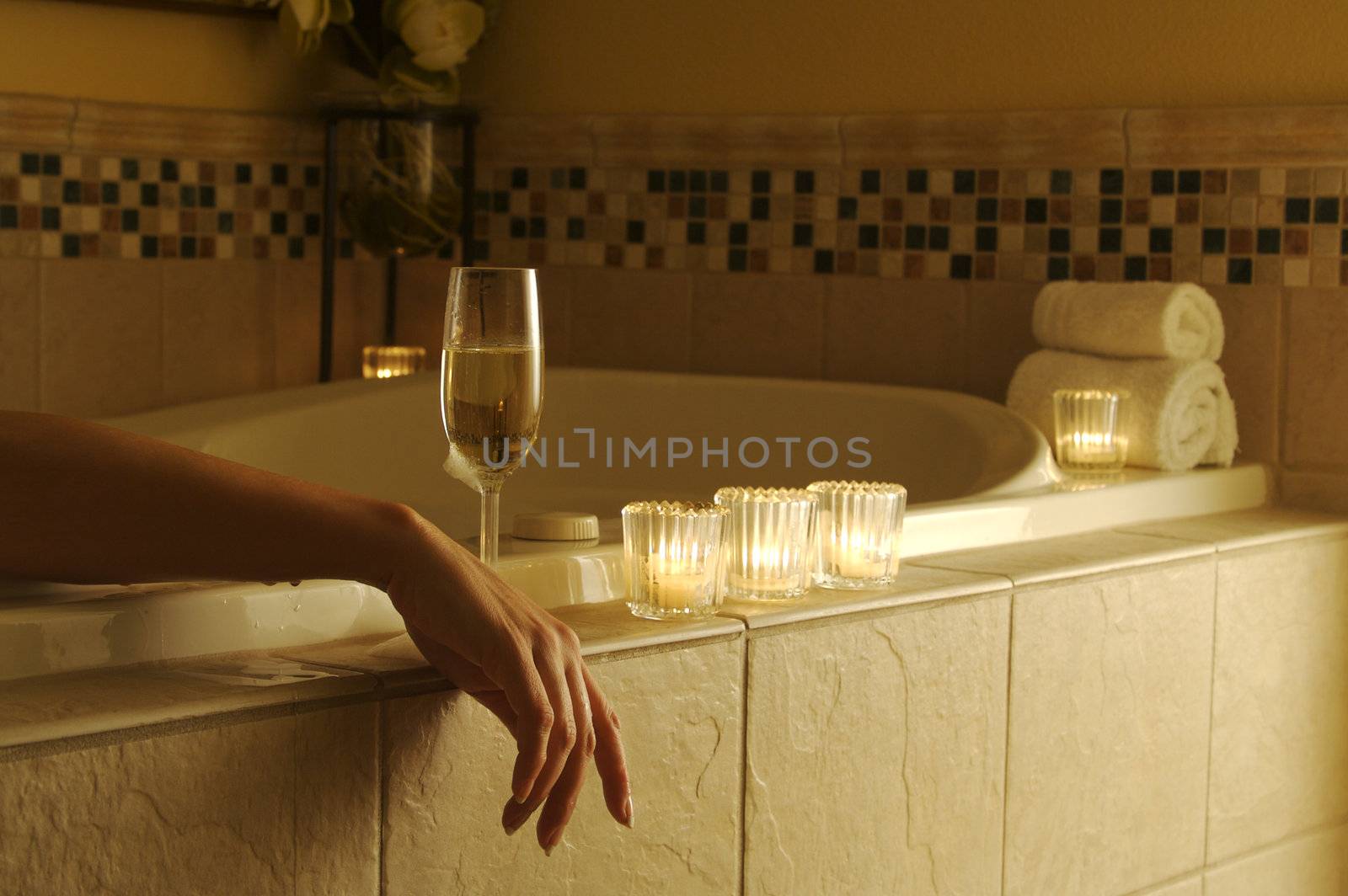Beautiful Woman in bubble bath with sparkling wine and candles surrounding her. 