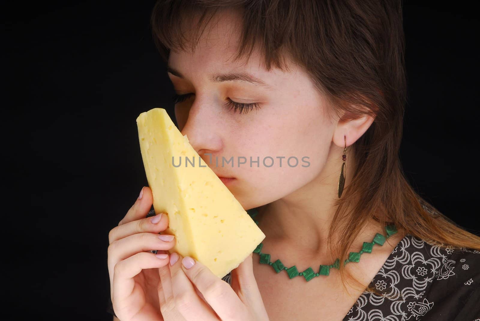 Beautiful woman smells piece of cheese on black background 