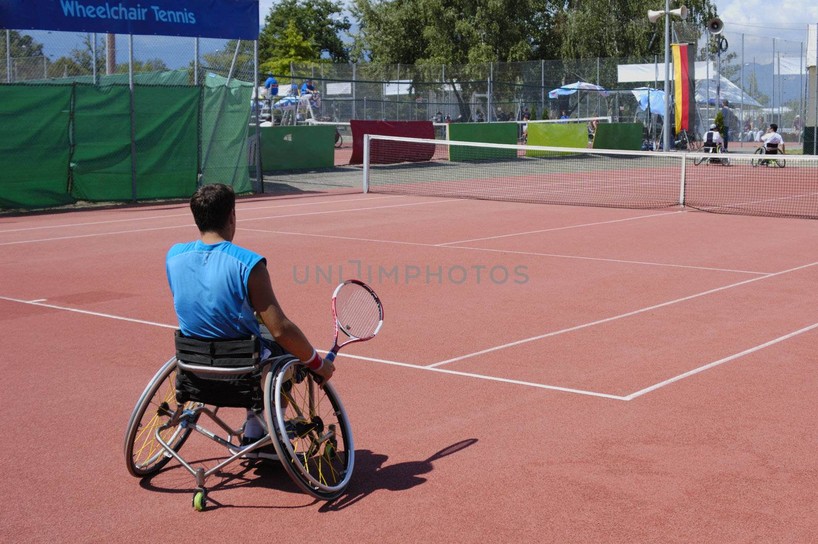 A wheelchair tennis player during a tennis championship match, preparing to take a shot.