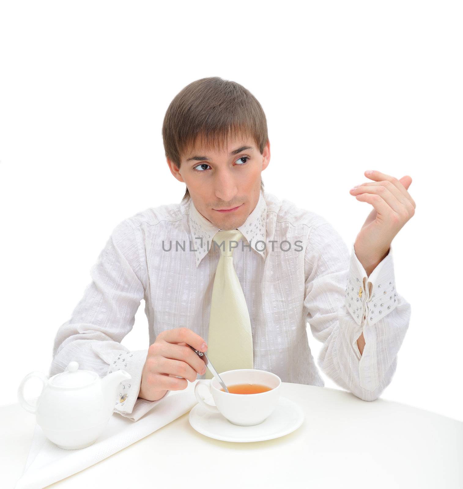 Young handsome  confident  man on white background. He sits for white table and drink tea from white cup.