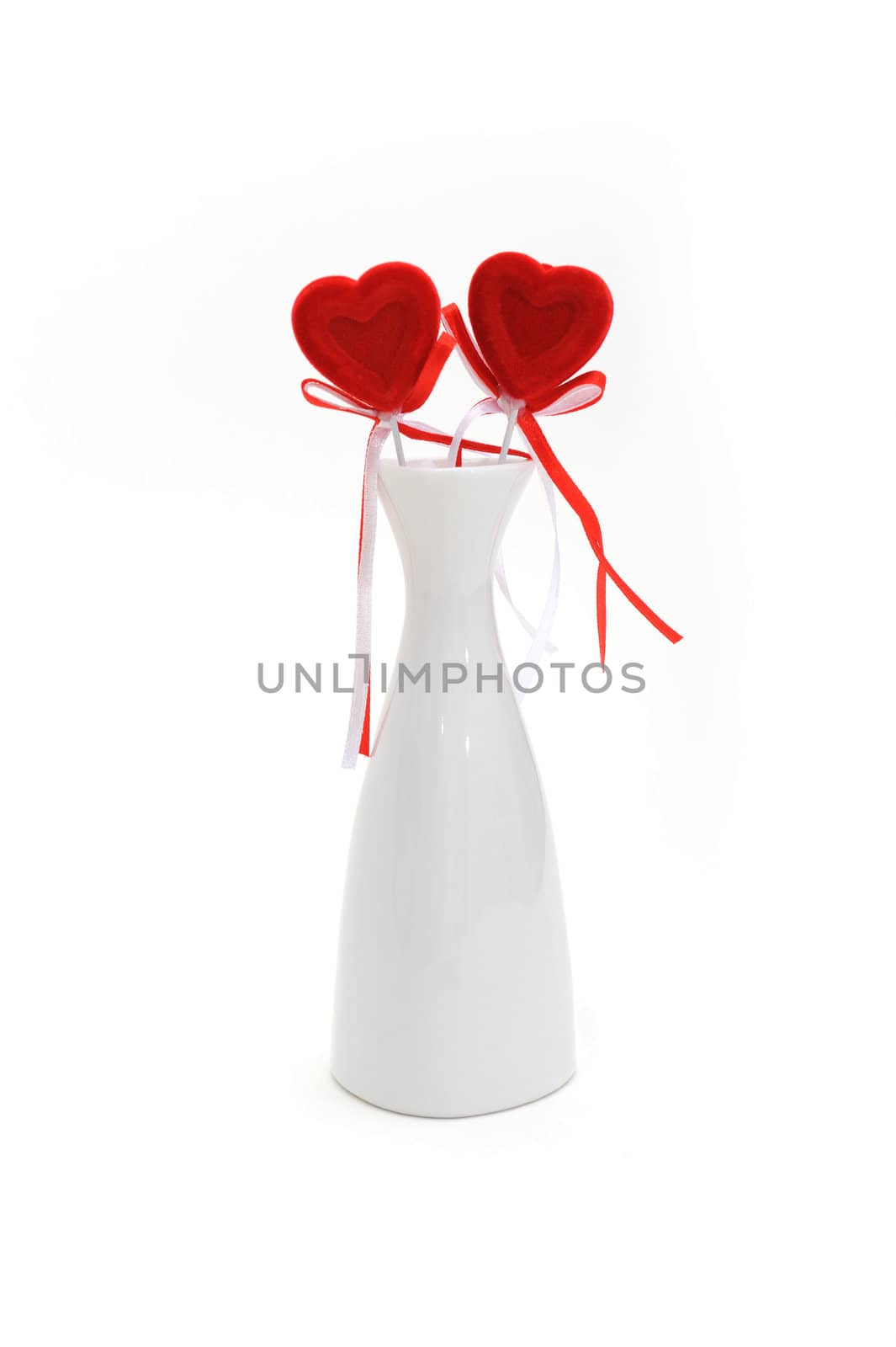 Two red plush hearts in white vase on white background.