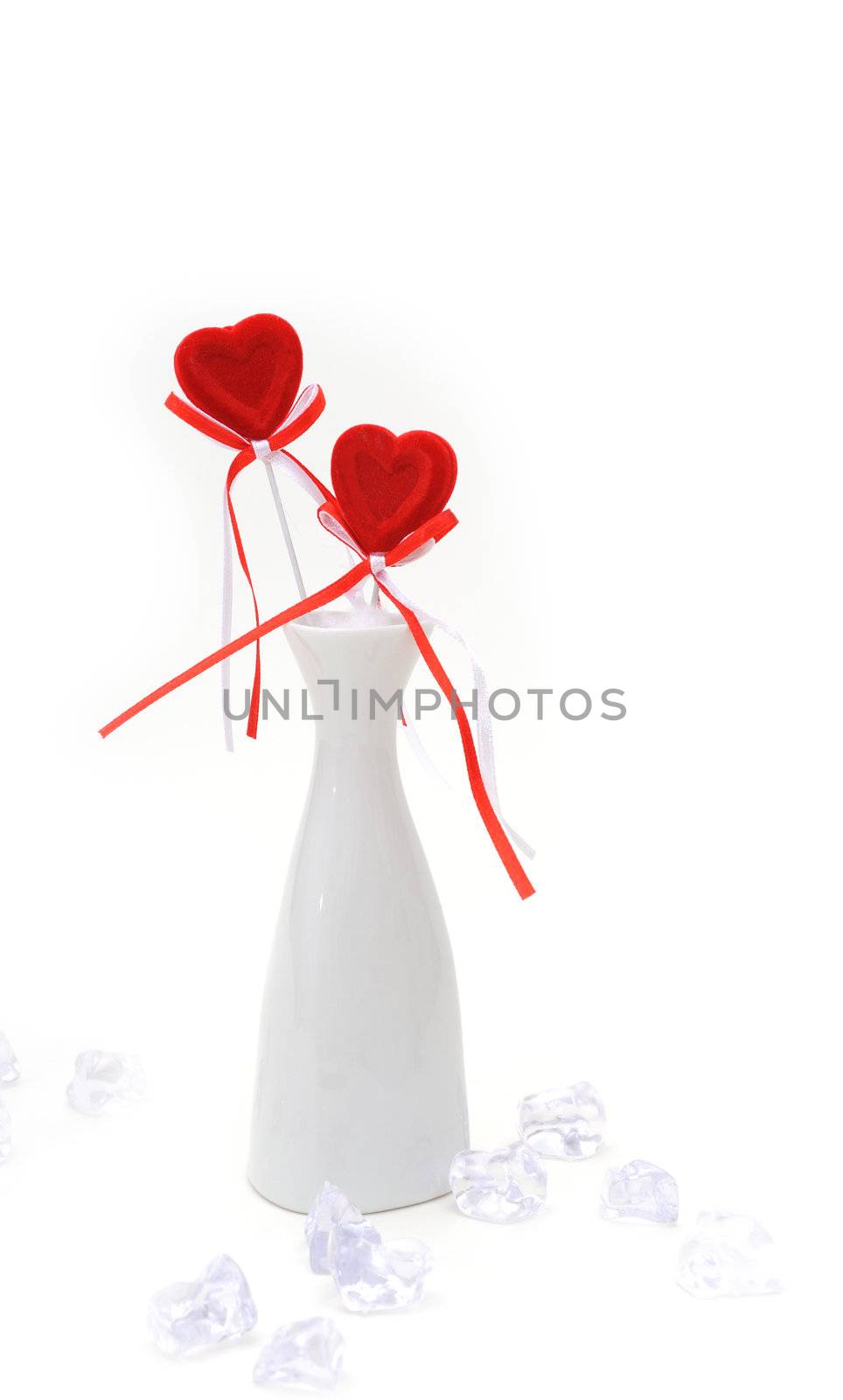 Two red plush hearts in white vase with cuts ice around on white background.