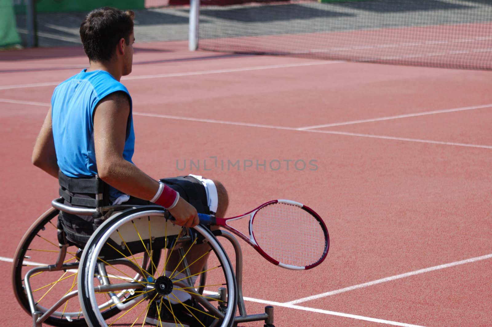 A wheelchair tennis player during a tennis championship match, waiting to take a shot. Space for text.