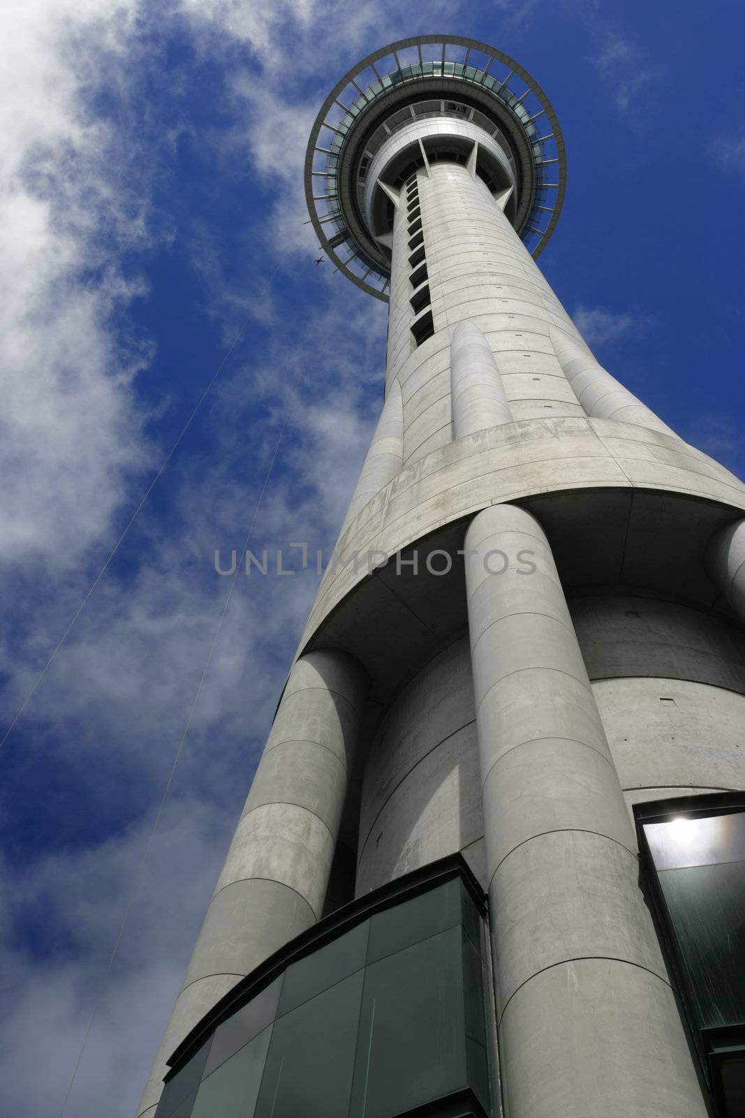 A worm's eye view of the Skytower in Auckland, New Zealand.  On the left of the platform, a jumper is falling from the jumping platform.
