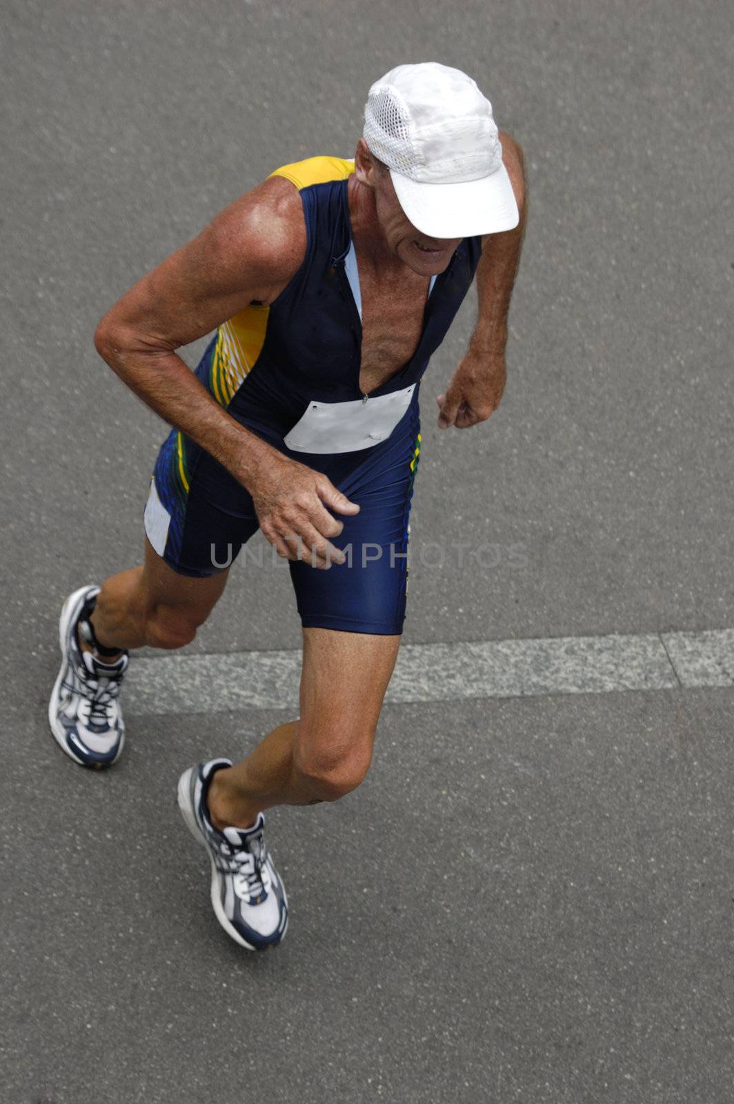 An older runner in a triathlon race, taken from above. Motion blur on his feet.