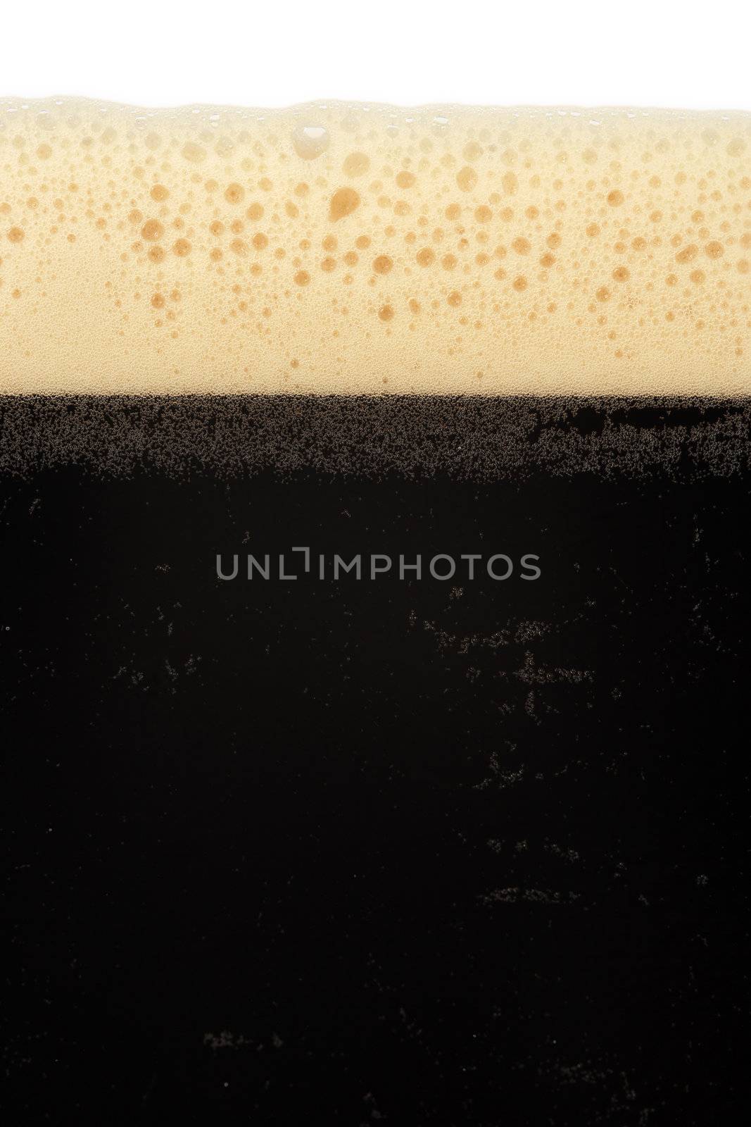 A macro image of a glass of stout beer or bitter.
