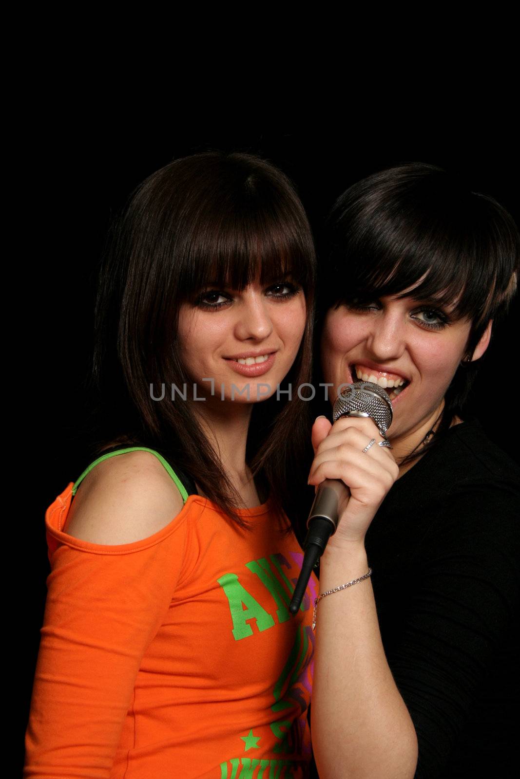 Two girls with a microphone, on black background