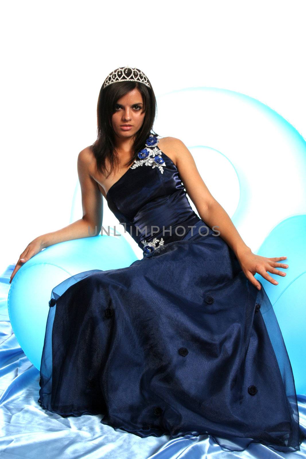 The girl in an blue evening dress and with a diadem, isolated on white