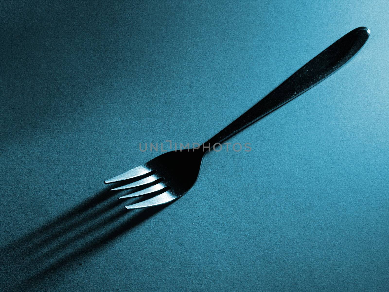 Diagonal fork and shadow against a a textured surface