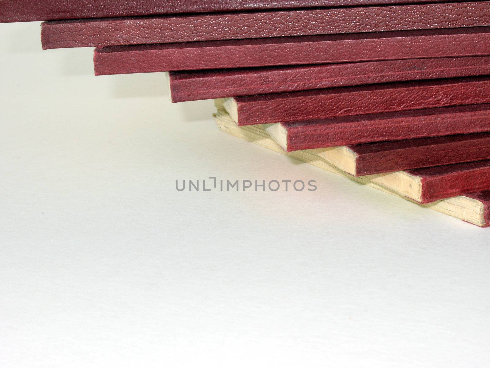 Pile of softcover books with red spines against light background