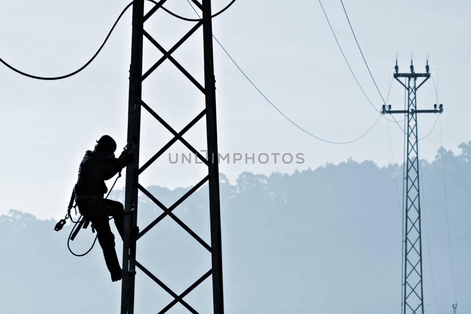 Backlit powerplant worker descending from tower