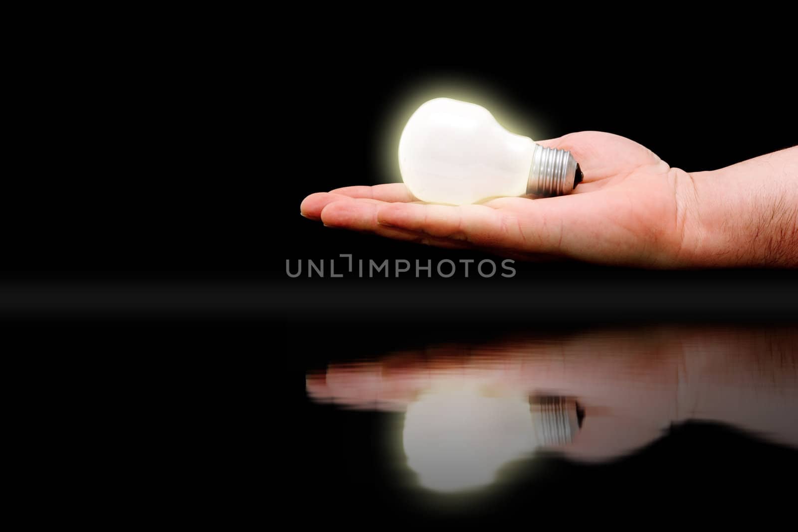 Concept : handing out bright ideas. Hand with lit bulb reflected on water surface