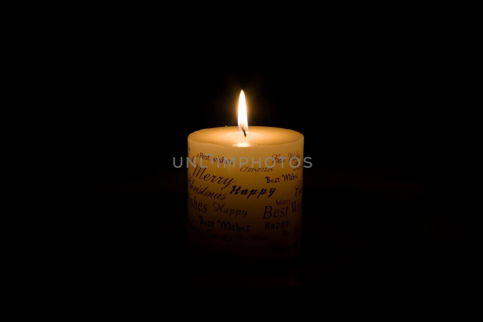 White Christmas candle lit on black background