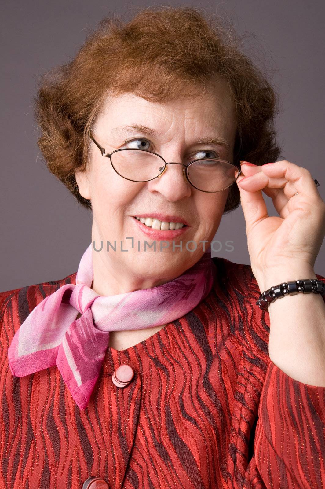 The pleasant elderly woman on gray background.