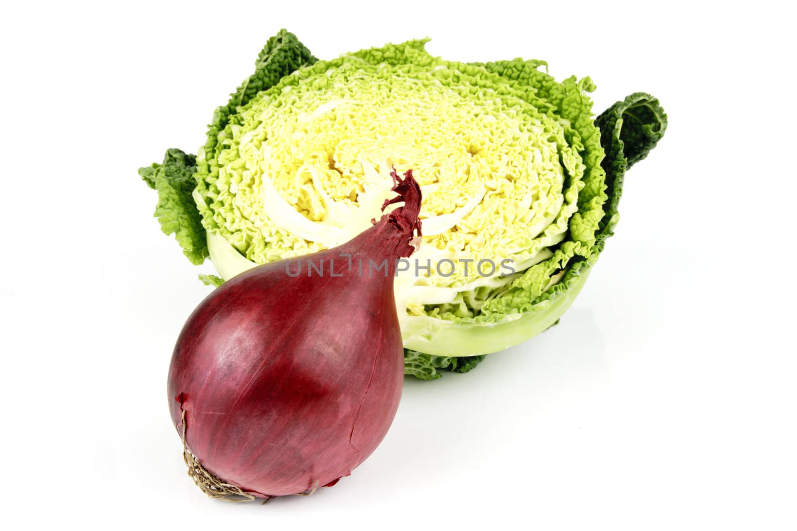 Half a raw green cabbage with a single raw red onion  on a reflective white background