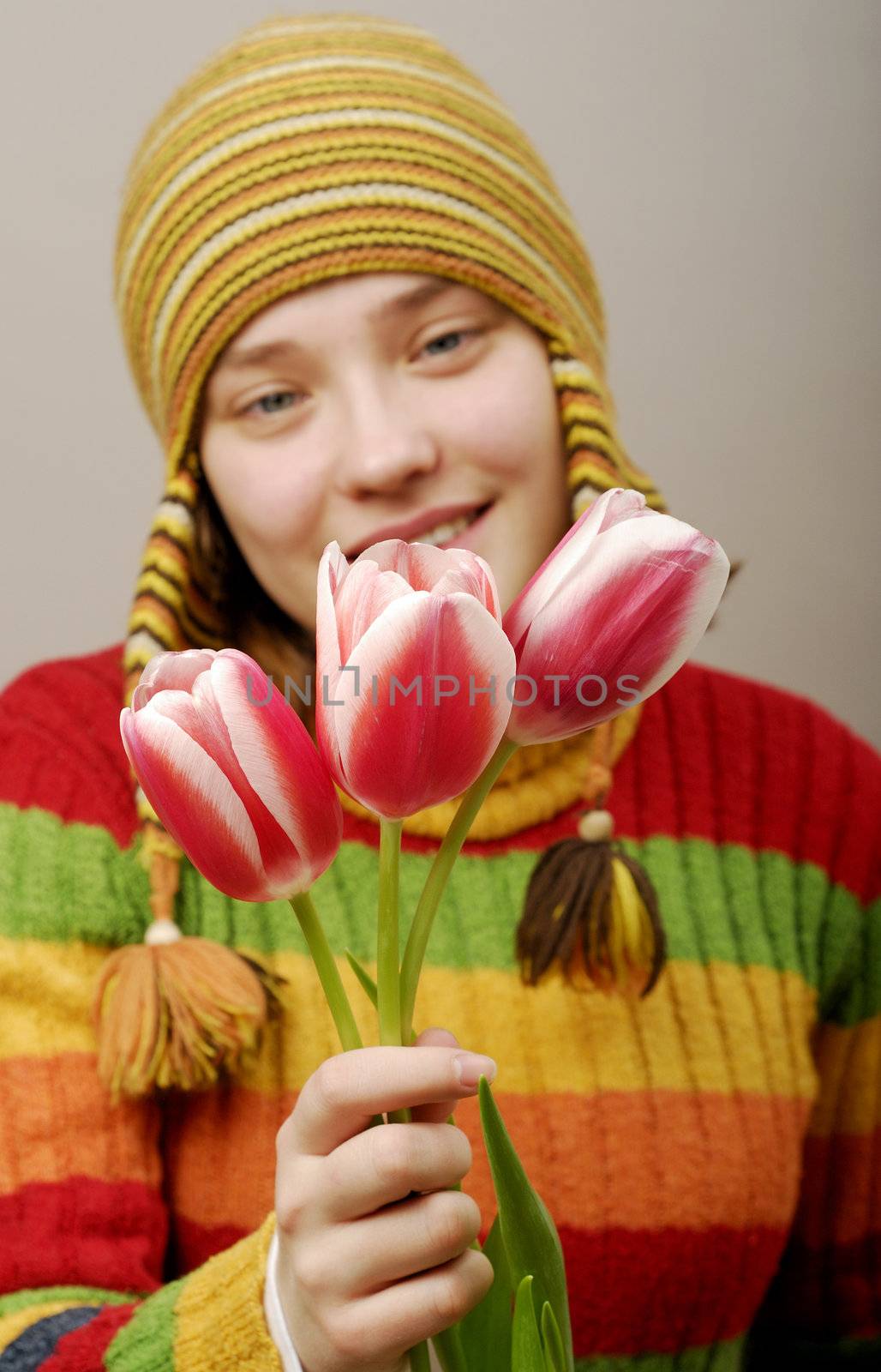 Girl in striped cap with three tulips.