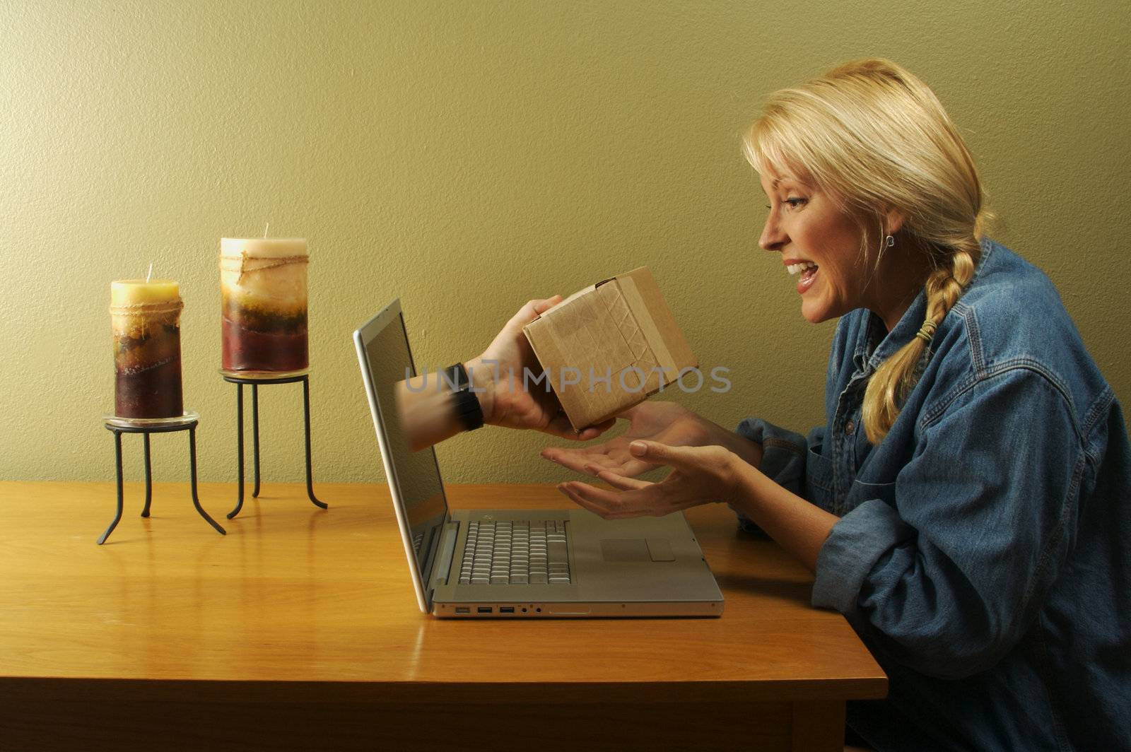 Attractive woman shocked to see a hand & her package coming through her laptop screen.