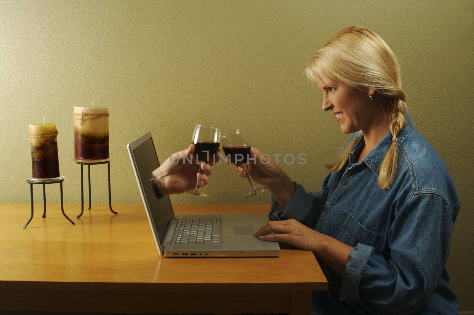 Attractive woman toasting a wine glasses with her online date coming through her laptop screen.