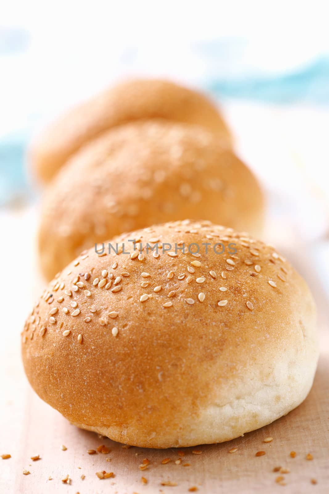 Closeup picture of three wheat buns with sesame against white background.