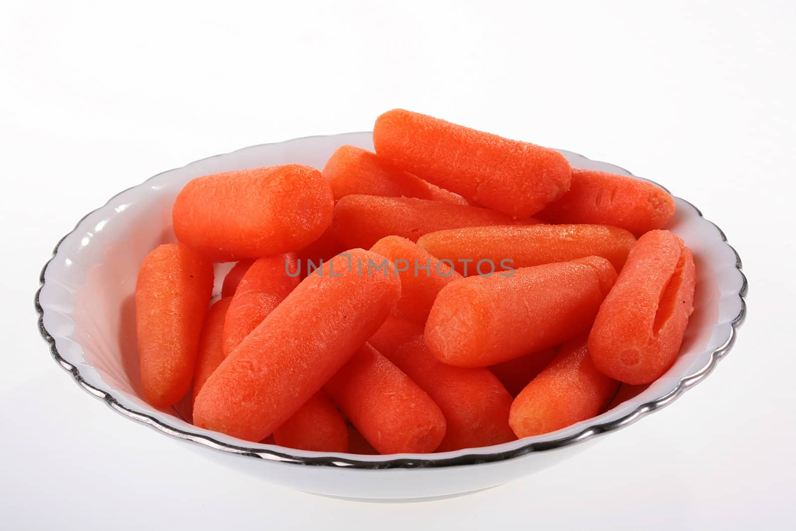 Small carrot as a light meal in a soup plate on a white background.