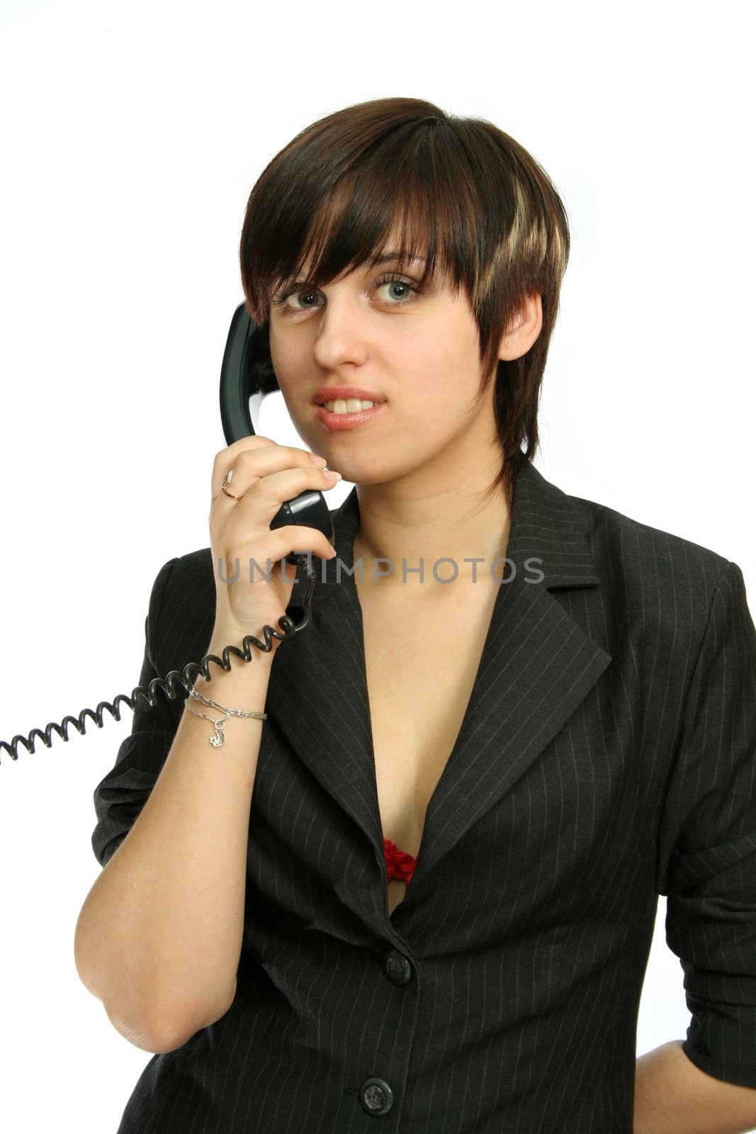 The young nice girl speaks by phone with a smile, isolated on white