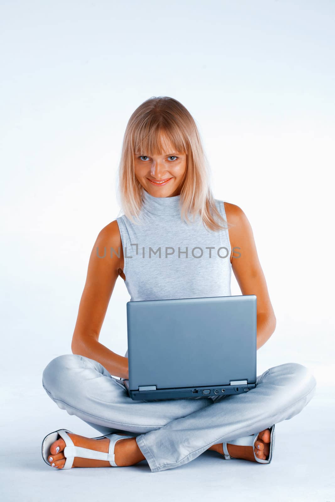 Smiling woman sitting with her legs crossed on the floor with laptop