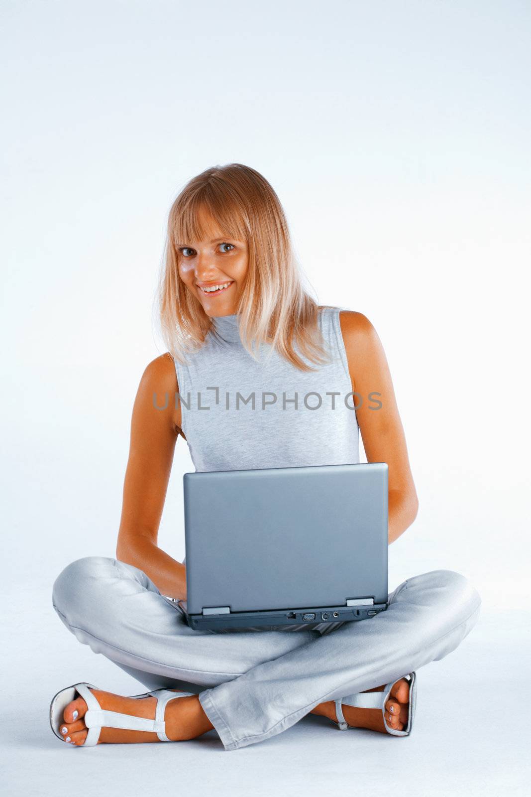 Smiling woman sitting with her legs crossed on the floor with laptop