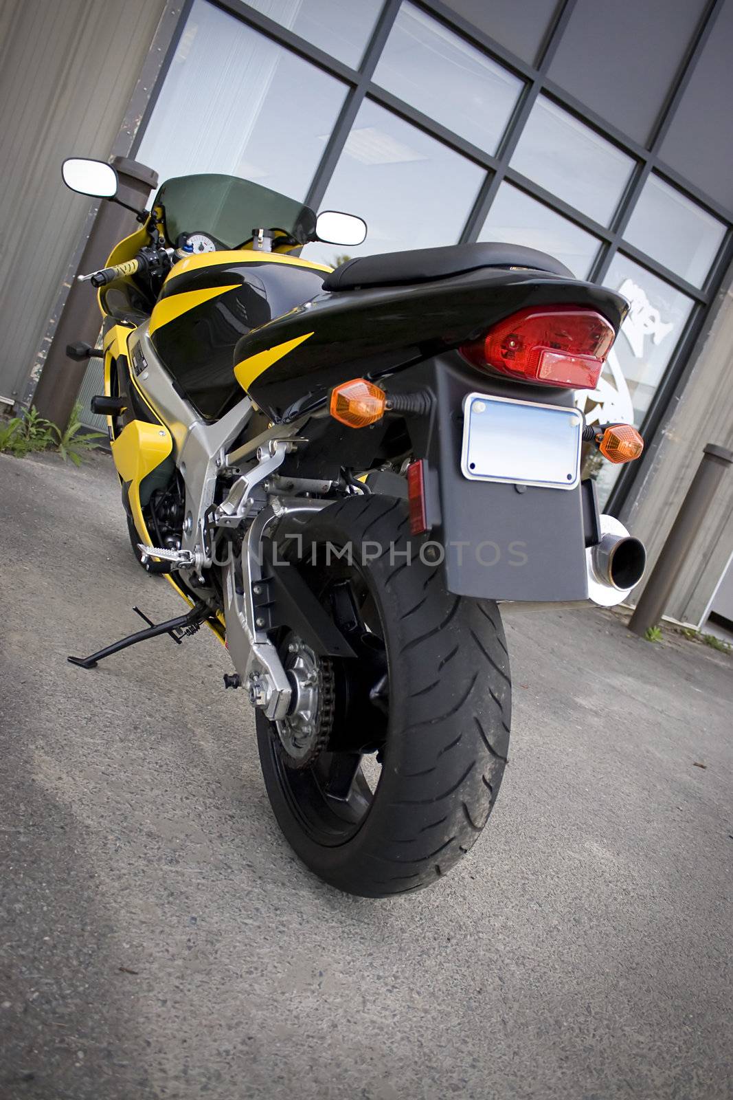 The rear view of a modern yellow motorcycle.