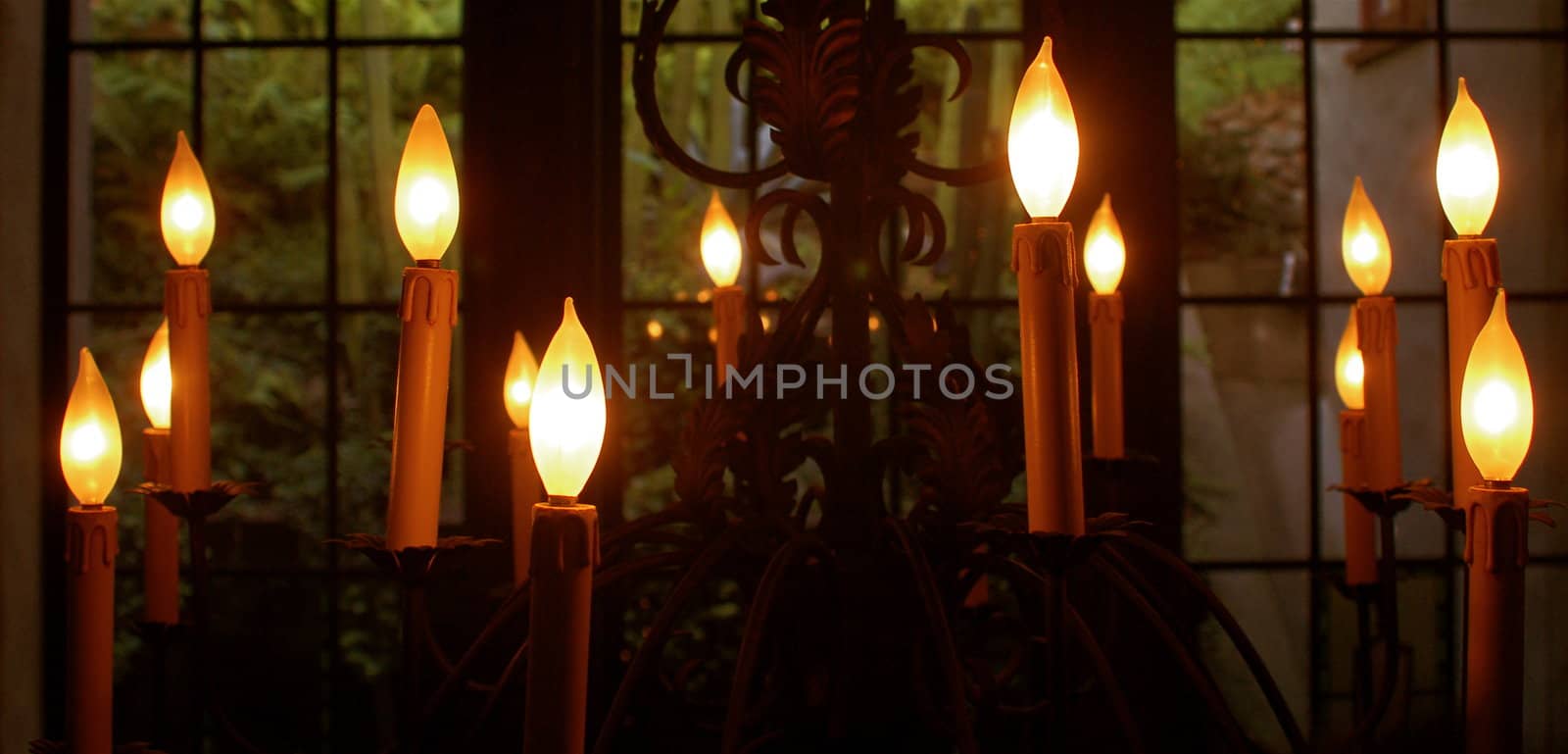 What appears to be numerous floating candles in front of an old fashioned, paned glass window