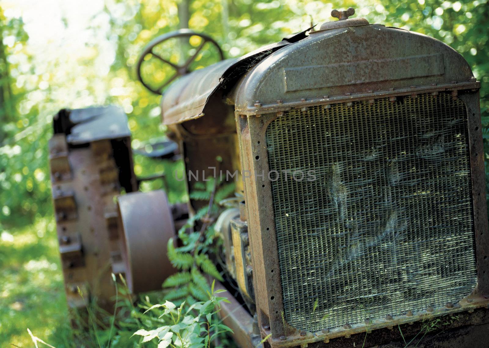 An old abandoned tractor left to rot in a field. Focus is on the radiator. Film scan.
