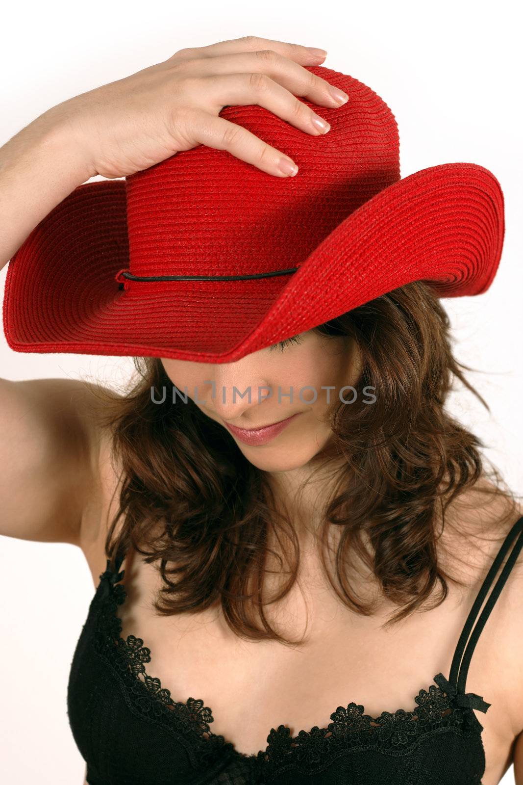 Image of a beautiful young woman putting a red cowboy hat on her head.
