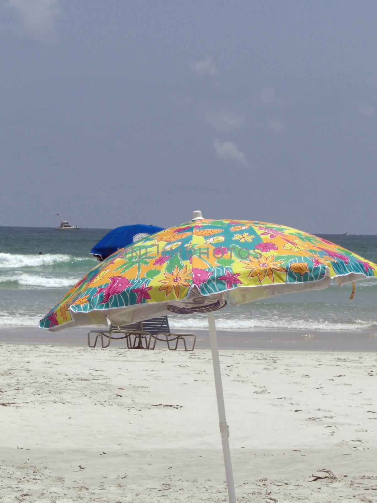 A colorful umbrella is standing in isolation at the beach.