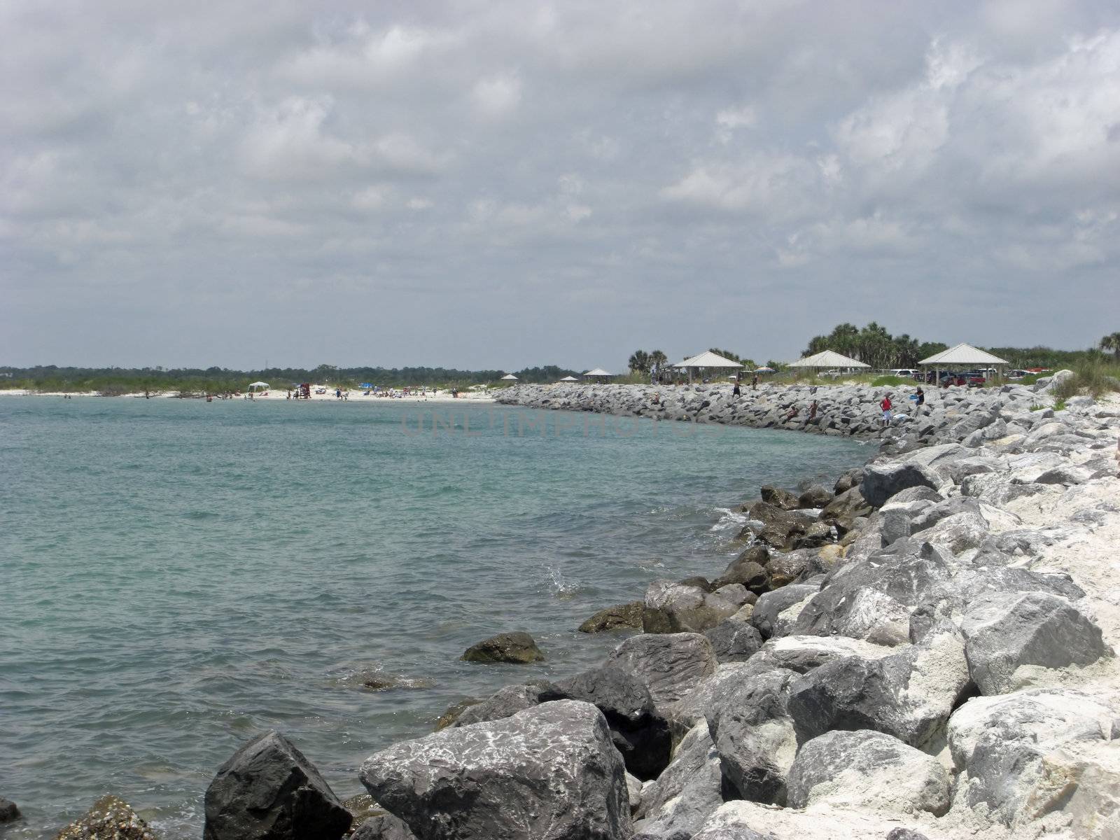 A pile of large rocks are lining the edge of an ocean