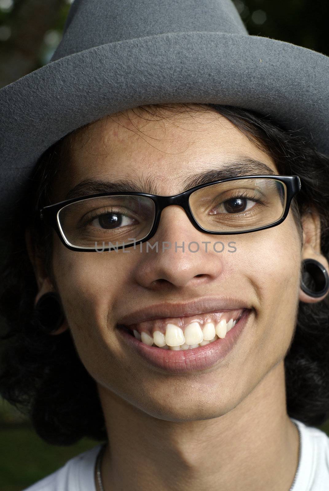 Smiling asian man with hat and pierced ears.