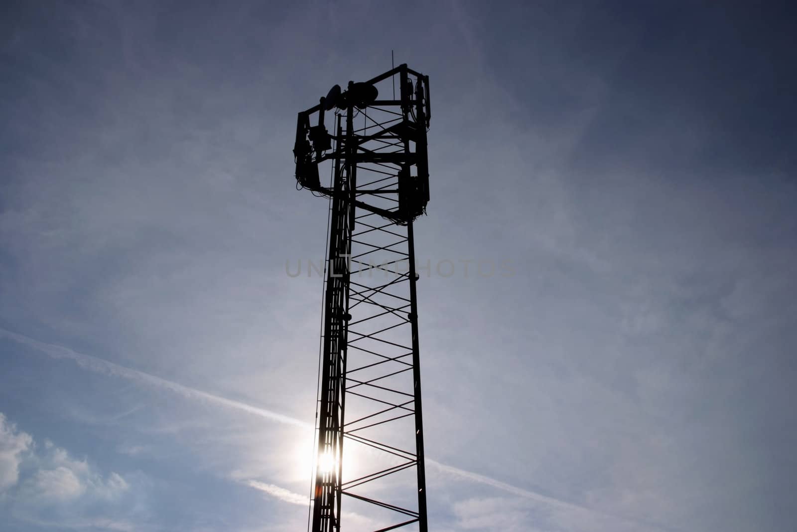Telecommunication mast with a stormy sky background and the sun setting