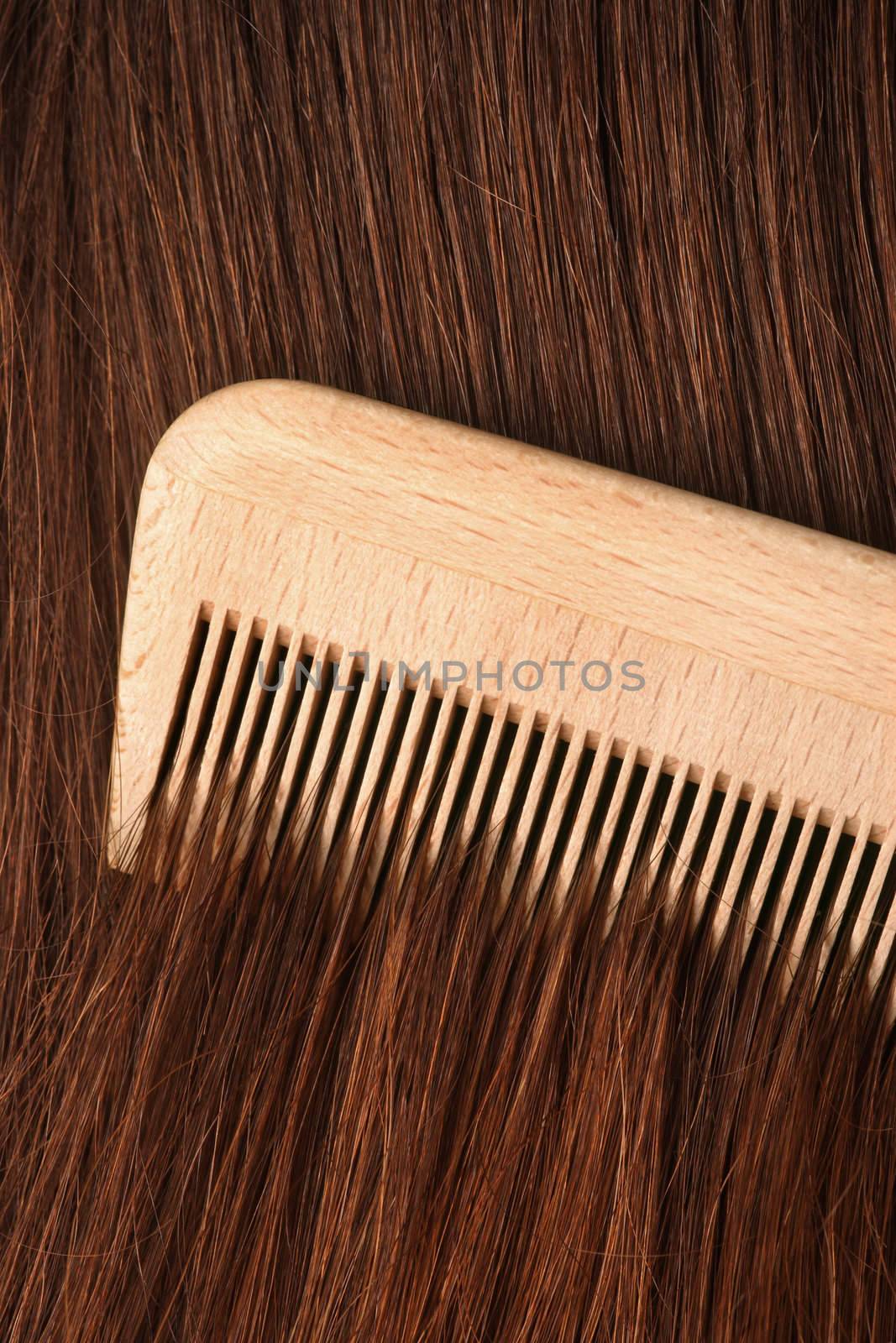 A comb running through long brown hair.
