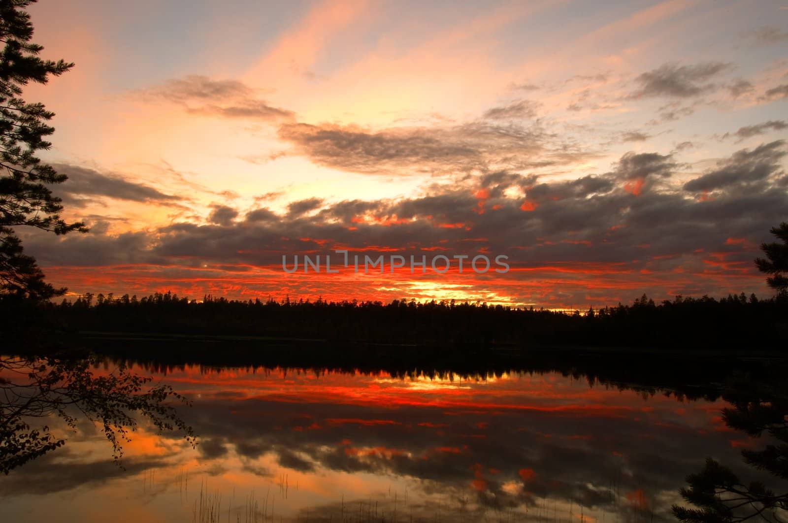 The cloudy sunset is reflected in wood lake