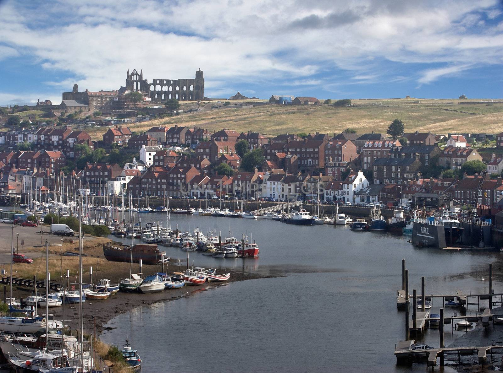Whitby estuary harbour and town, with the ruined abbey on the hill above.