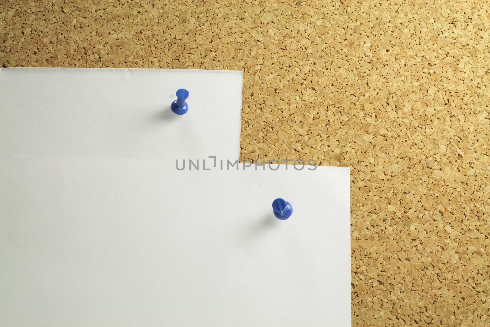 two pieces of white notepaper on a cork board background