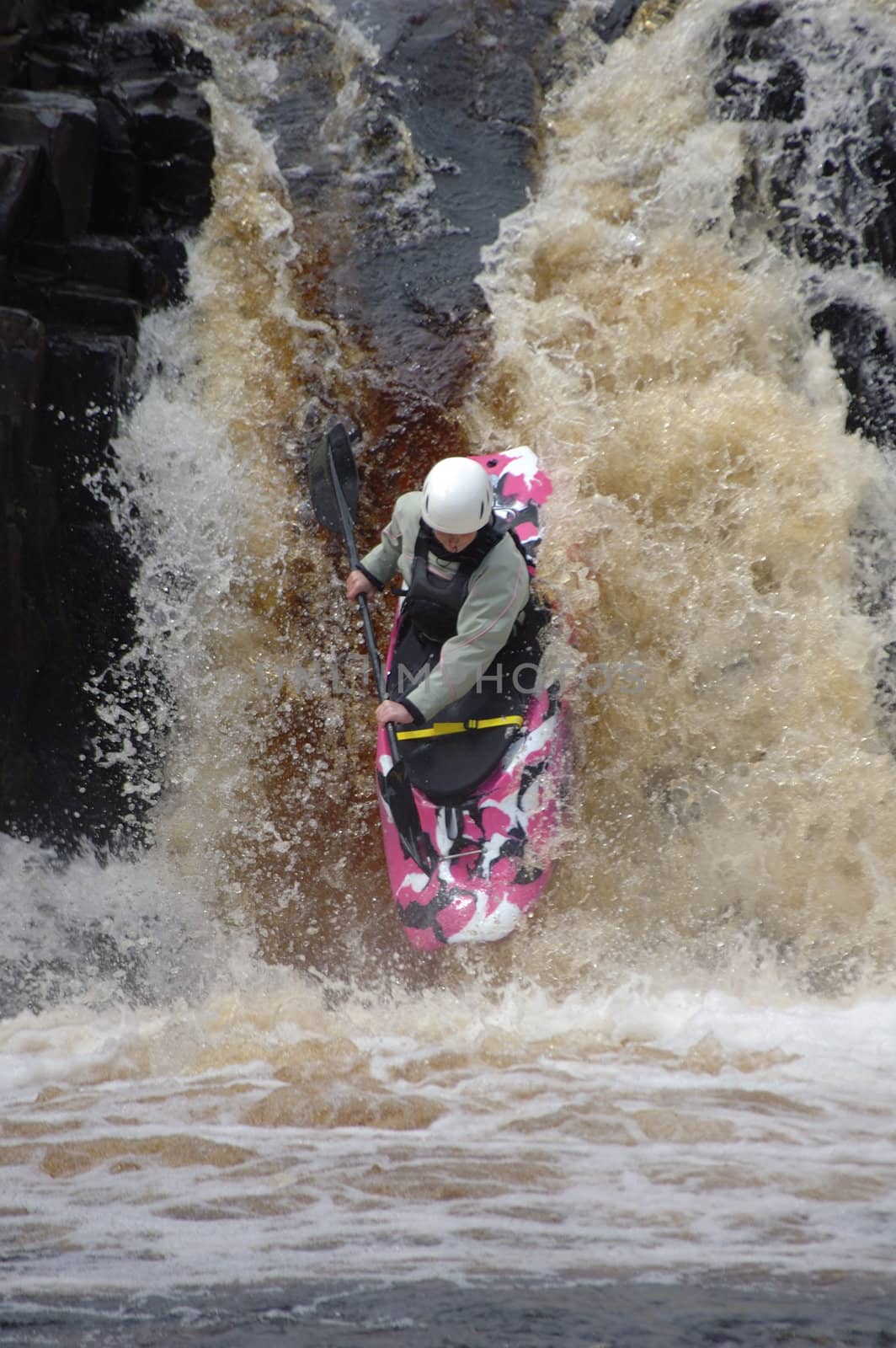 A canoeist, shooting a raging waterfall, on the Tees River, UK.