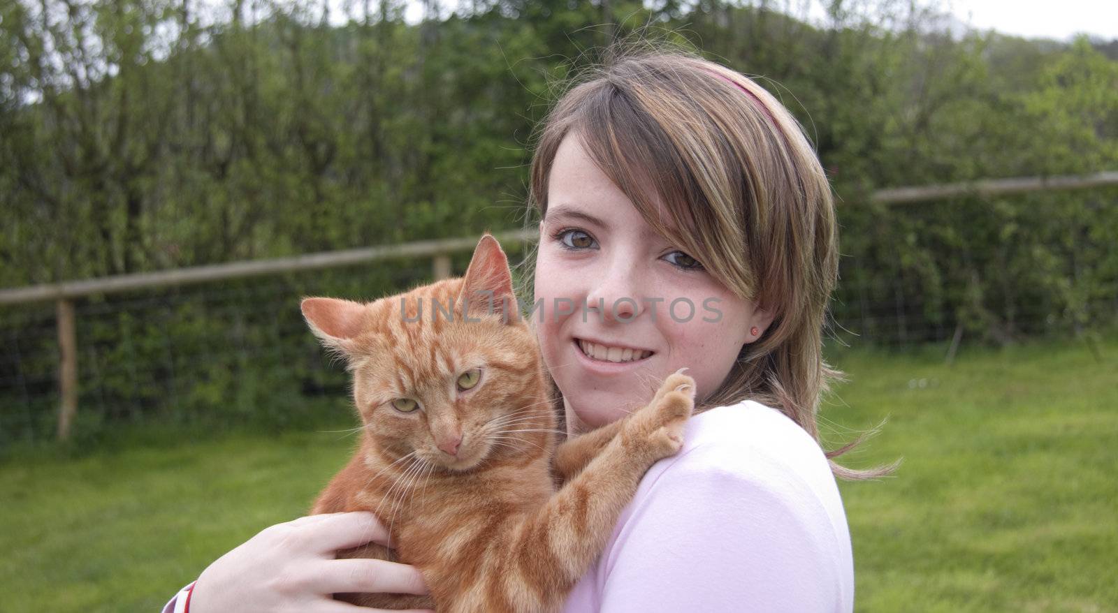 Teenage girl hugs her cat.